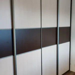 Moderná vstavaná skriňa na mieru s posuvnými dverami v kombinácii bielej a tmavohnedej farby s vodorovným dekoratívnym pásom.